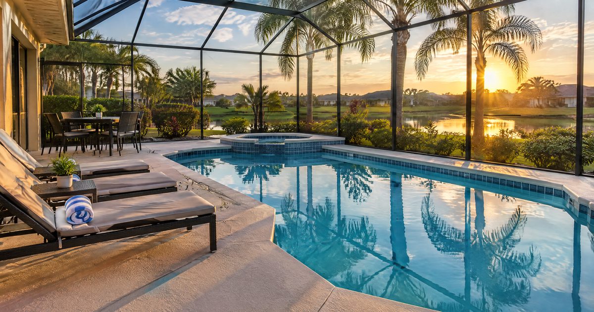 Screened pool and patio of a Central Florida vacation home with palm trees at sunset